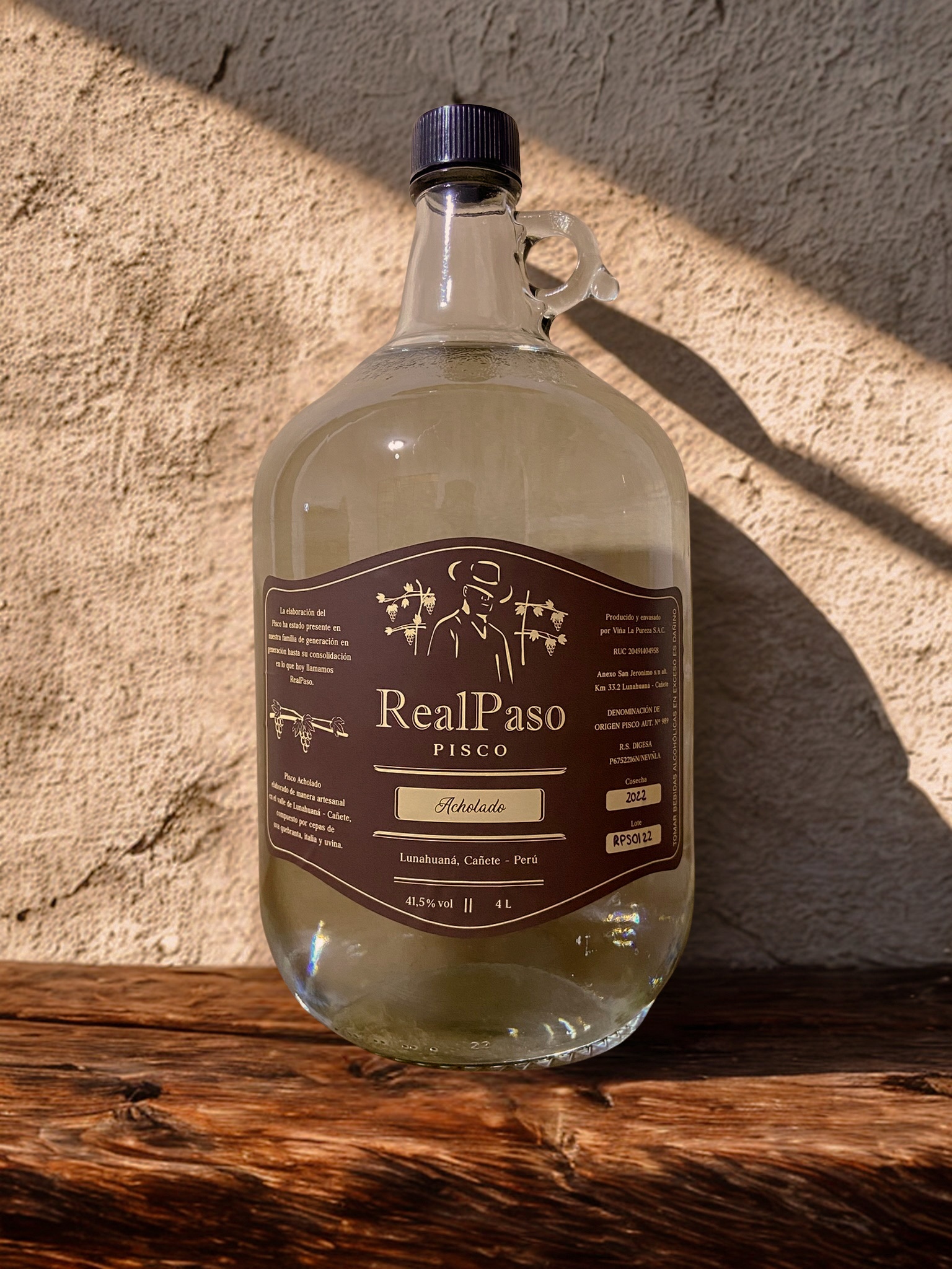 Botella de 4 litros de Pisco RealPaso Acholado sobre madera rústica